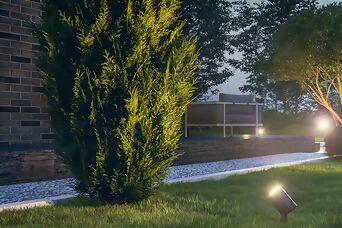 Spot lumineux LED mettant en valeur les plantes et les arbres dans un jardin moderne en soirée.
